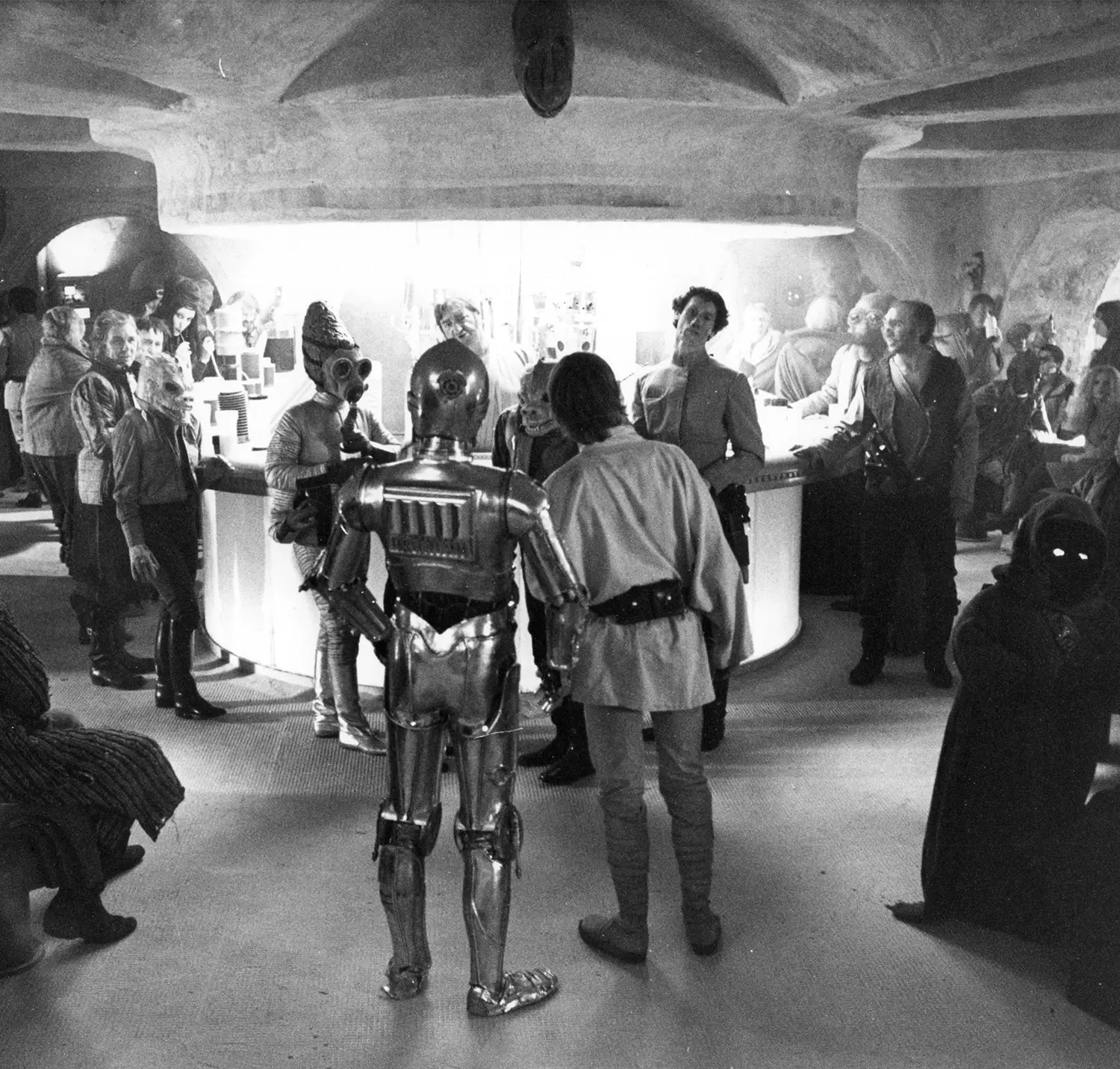 Luke and C3PO peer into a seedy bar filled with different kinds of alien types, who are staring back at them.