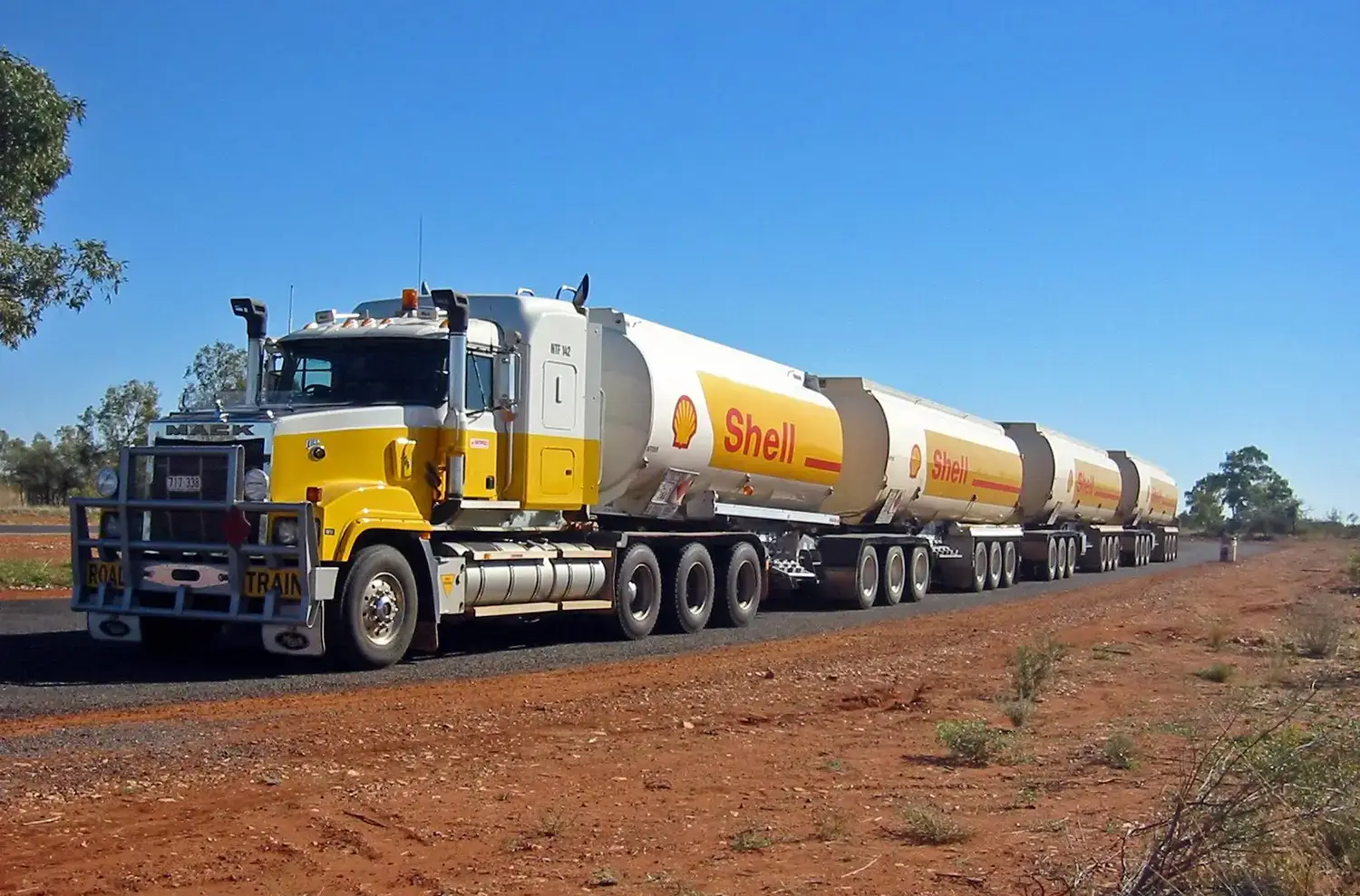 A tanker truck with four semi-trailers stretched across a road that’s surrounded by Australia’s characteristic red earth.